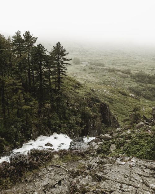 Free A tranquil view of a mist-covered mountain landscape featuring a cascading waterfall. Stock Photo