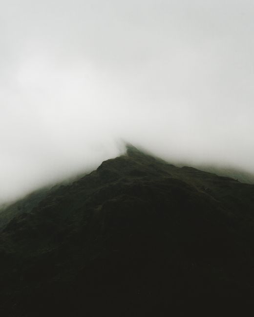 A scenic view of a mountain peak enveloped in thick mist, creating a moody atmosphere.