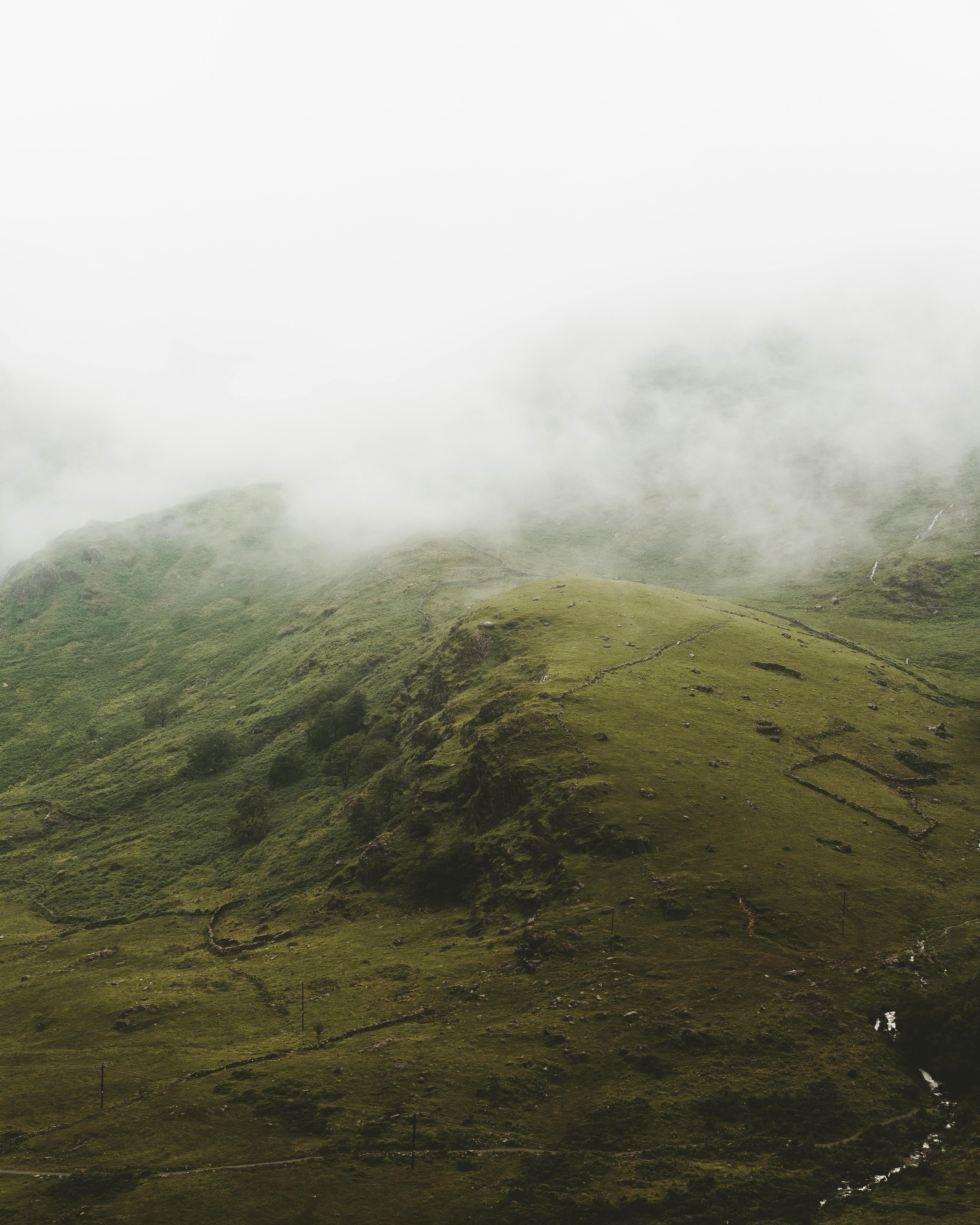 从空中俯瞰雾霭笼罩的山丘，营造出一种宁静而神秘的乡村氛围