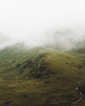 从空中俯瞰雾霭笼罩的山丘，营造出一种宁静而神秘的乡村氛围