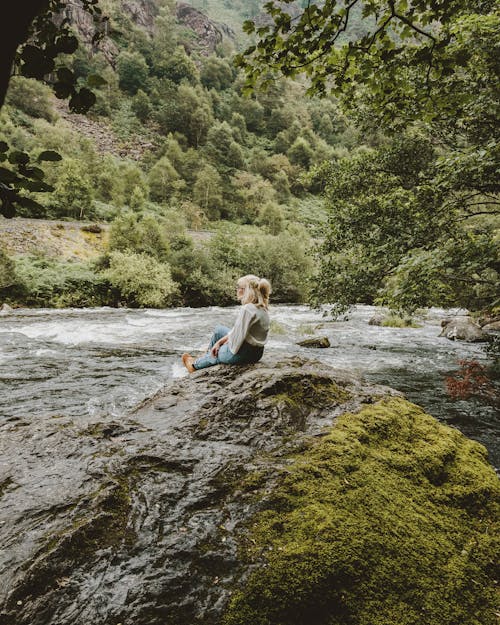 Femme Assise Près D'une Formation Rocheuse Au Bord De La Rivière