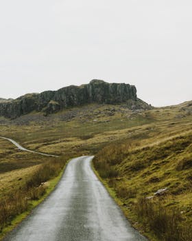 一条宁静的乡村道路在阴沉的天空下蜿蜒穿过崎岖的山丘