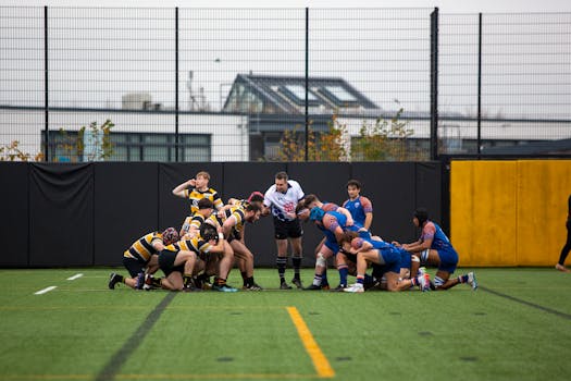 Rugby teams battling in a tense university match outdoors on an artificial turf field.