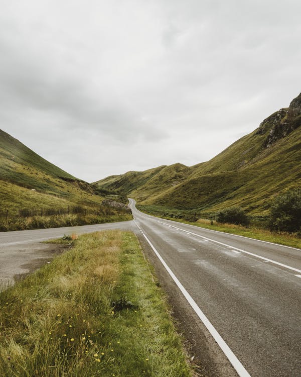 Concrete Roads Surrounded By Green Hills And Mountains