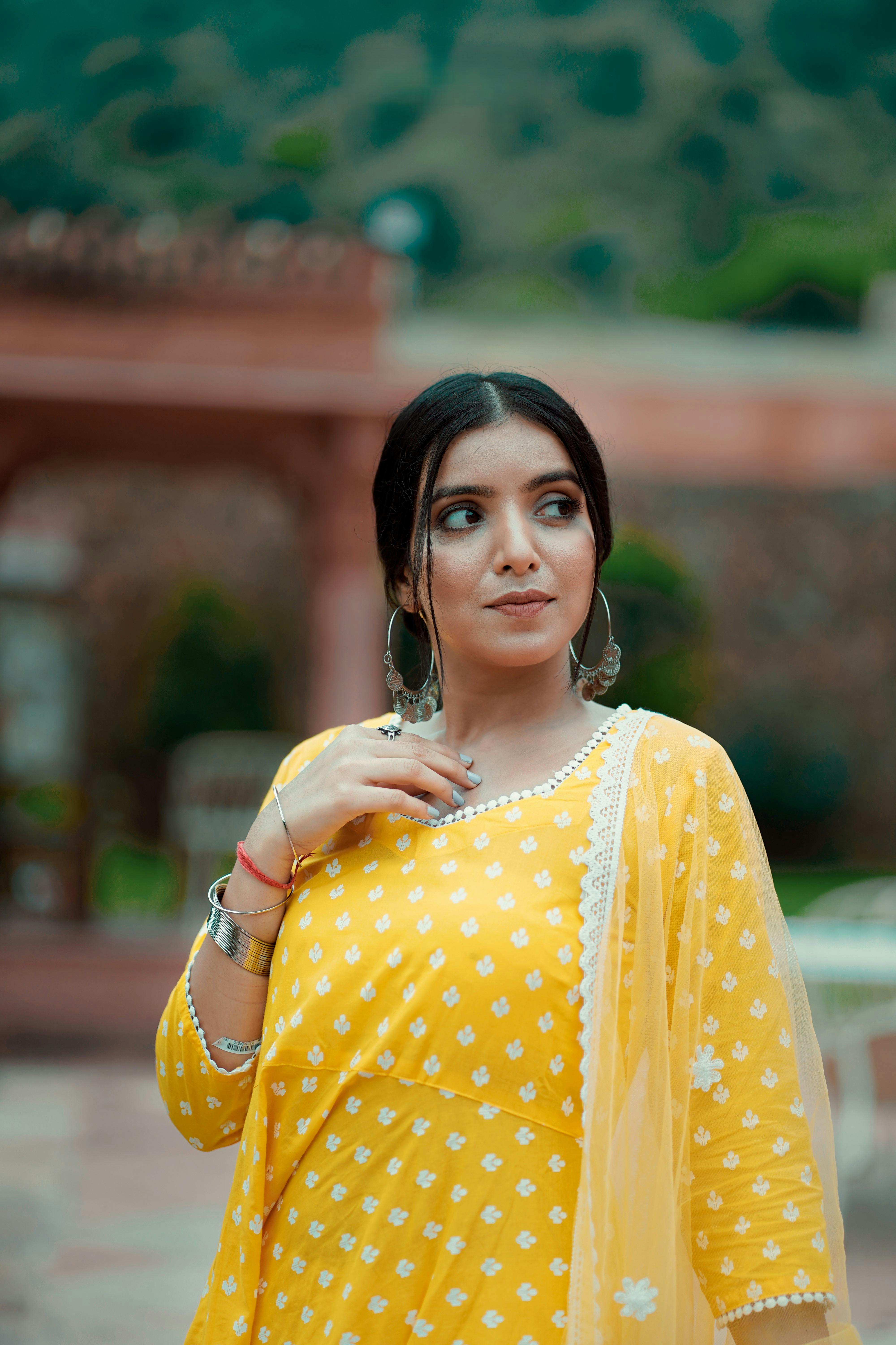 Elegant woman posing in a bright yellow traditional dress with mountain backdrop.