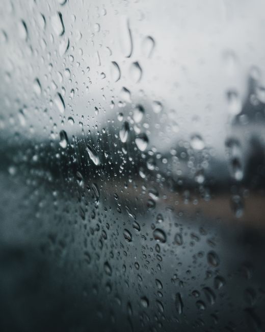 Close-up of raindrops on a window, evoking a moody and introspective atmosphere.