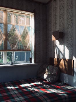 A cozy and rustic bedroom corner, bathed in natural sunlight with a patterned blanket and soft cushions.