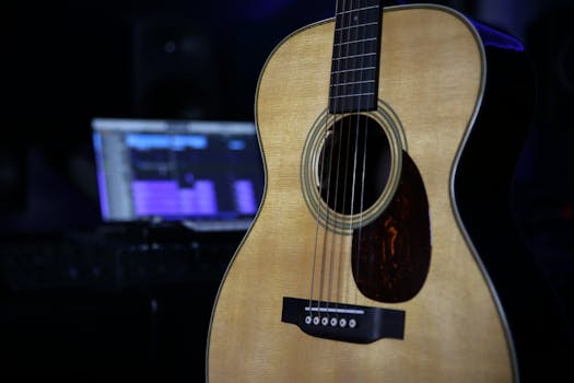 Close-up of an acoustic guitar in a modern home studio environment with dim lighting.