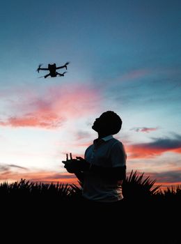 Man operates drone against vibrant sunset sky in Nairobi, Kenya.