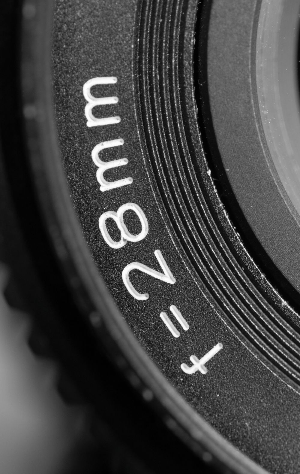 Black and white macro of a lens barrel focal-length marking — photo by DUONG QUACH on Pexels