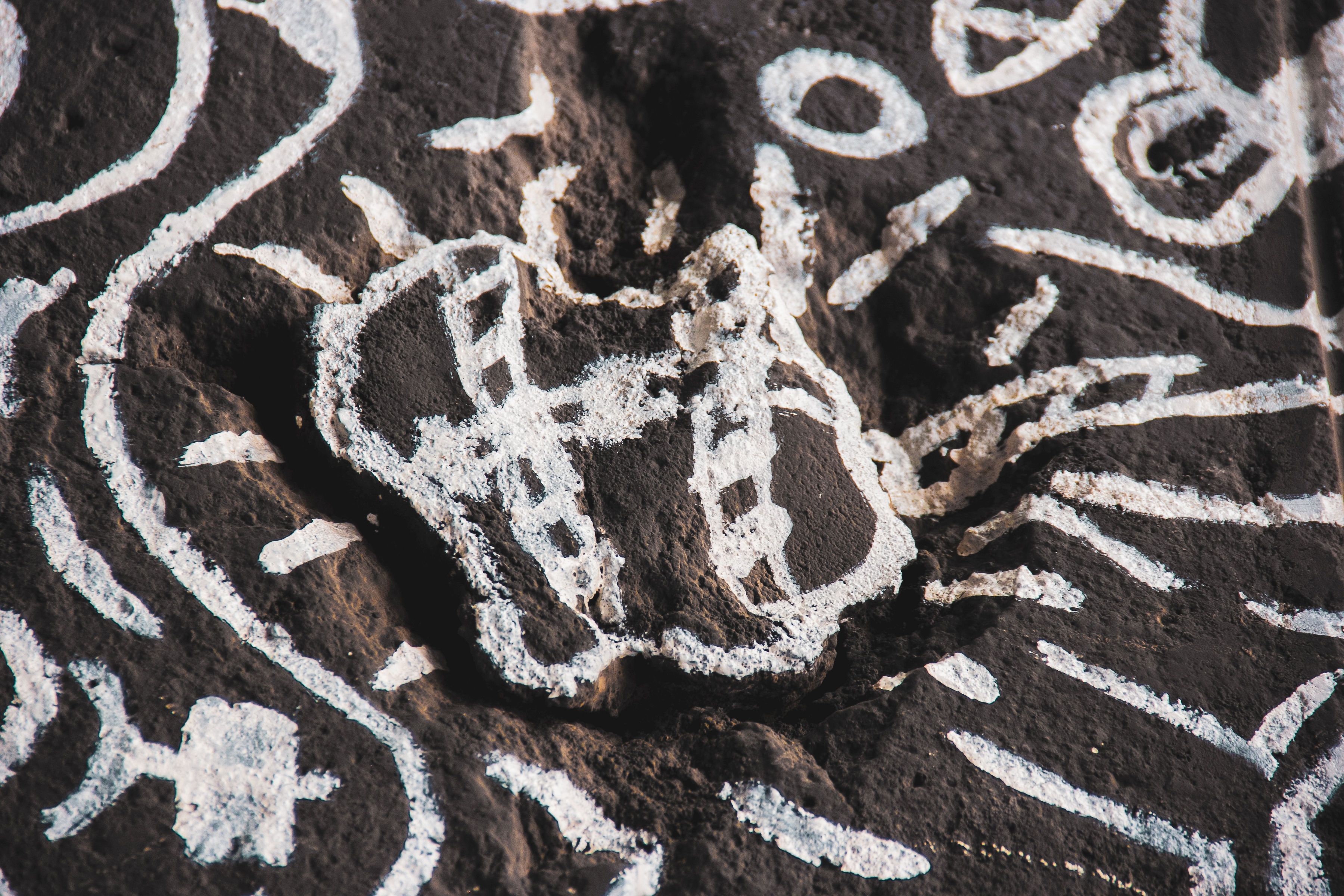 Rock Art with White Chalk Patterns on Dark Surface · Free Stock Photo