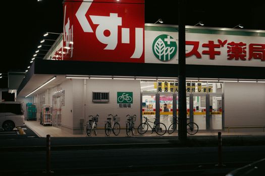 Evening scene of a pharmacy in Toyohashi, Aichi with bicycles outside.