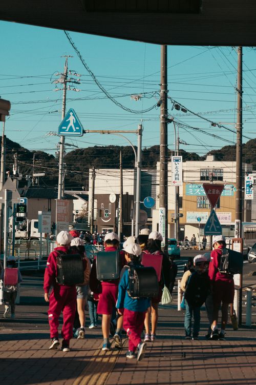 Free Group of children with backpacks crossing a street in Toyokawa, Japan on a sunny day. Stock Photo