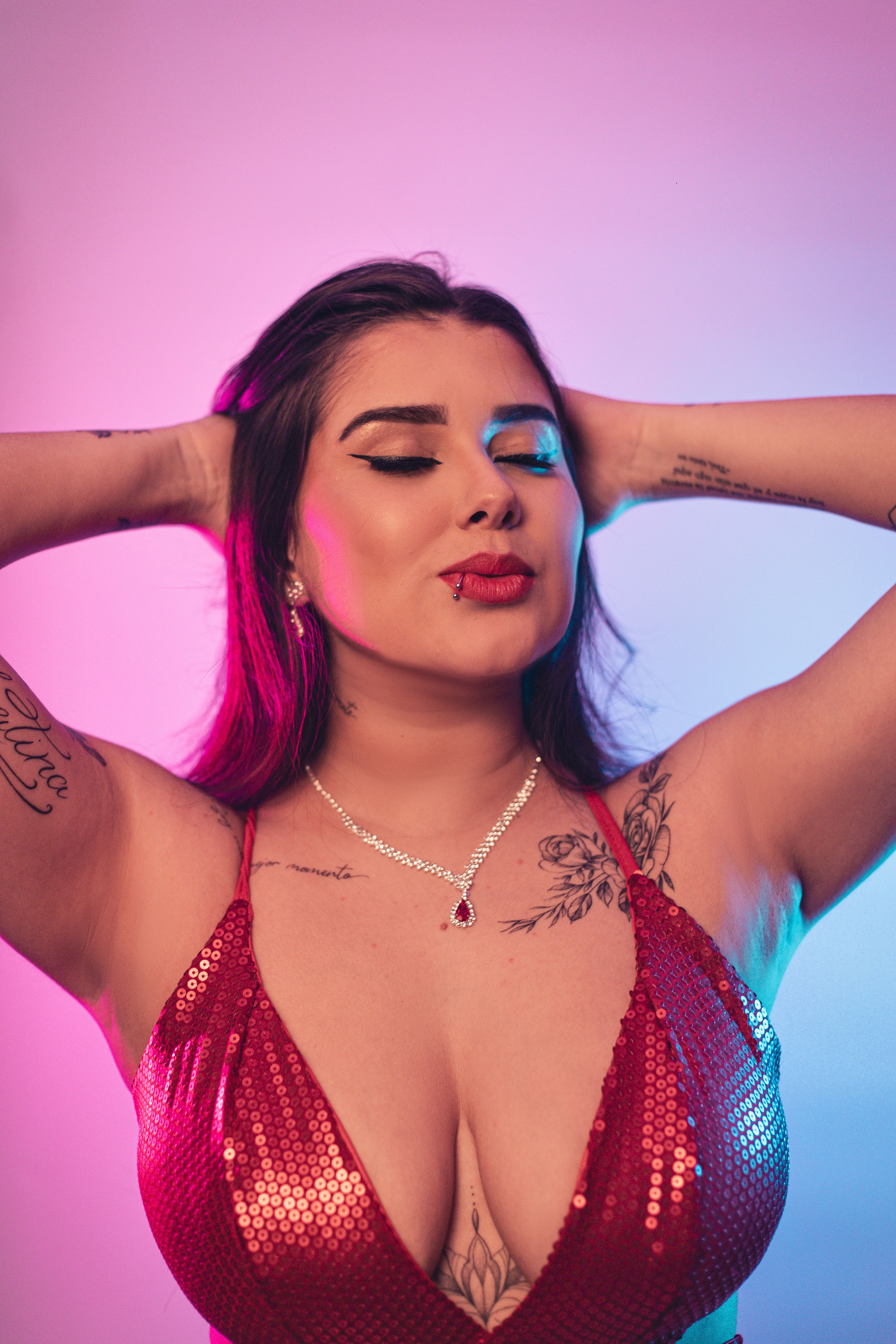 A confident woman in a red sequin dress poses stylishly against a colorful background.