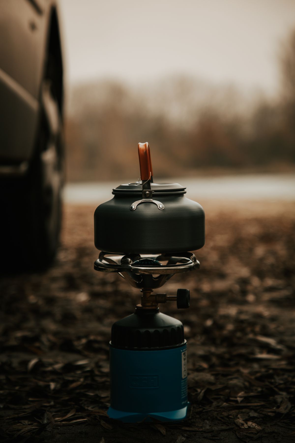 Portable camping stove with cookware on a forest floor