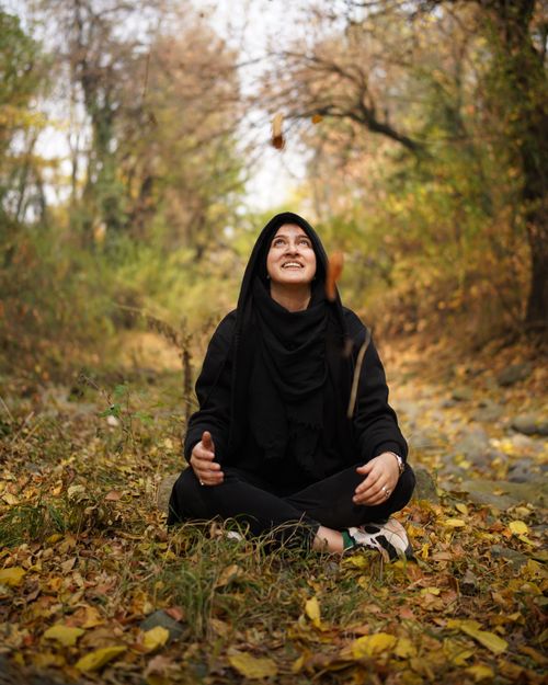 Free A woman in black attire enjoys the vibrant autumn foliage in a serene forest setting. Stock Photo