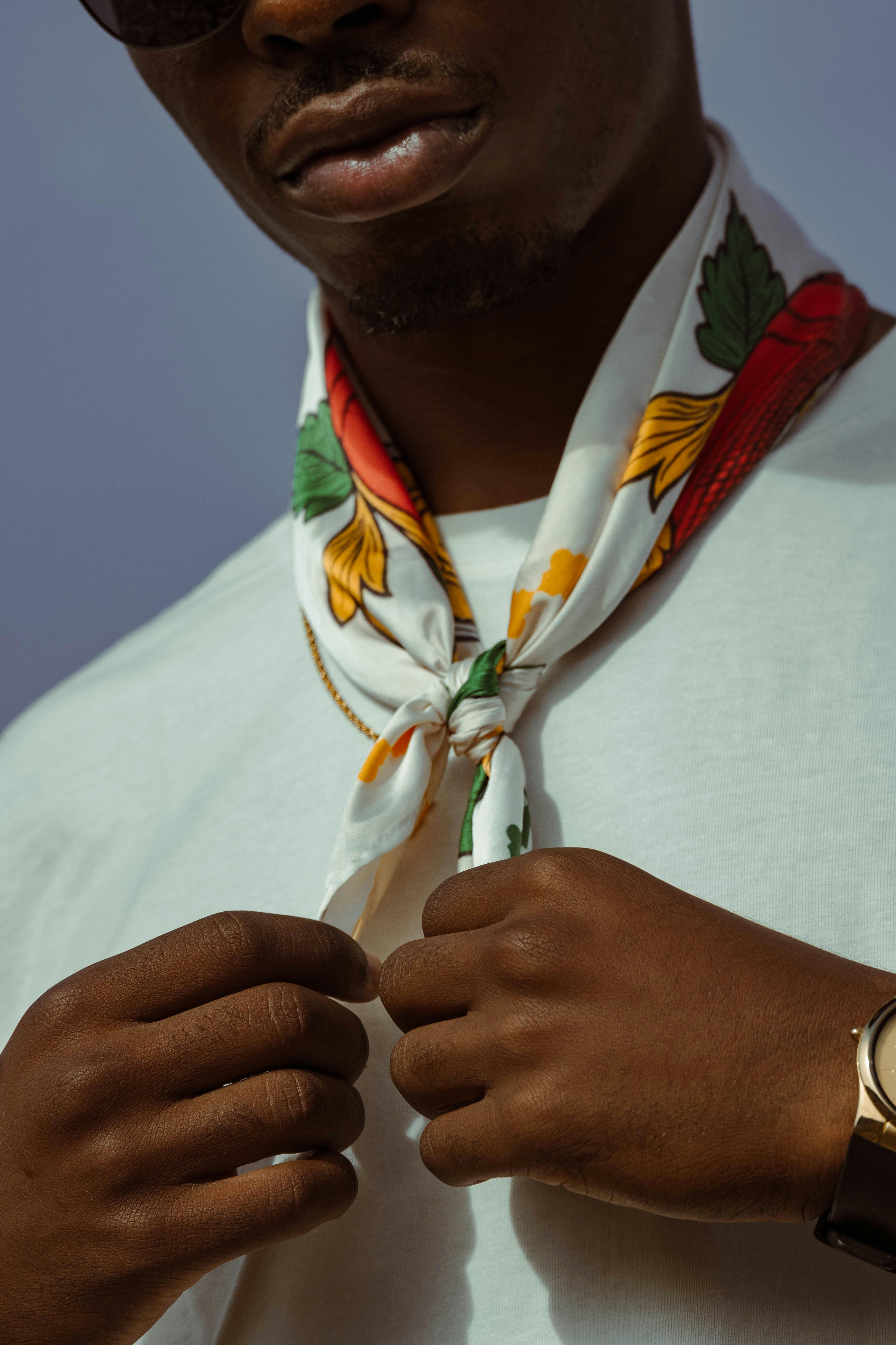 Close-up of a person adjusting a floral necktie, showcasing modern fashion style.