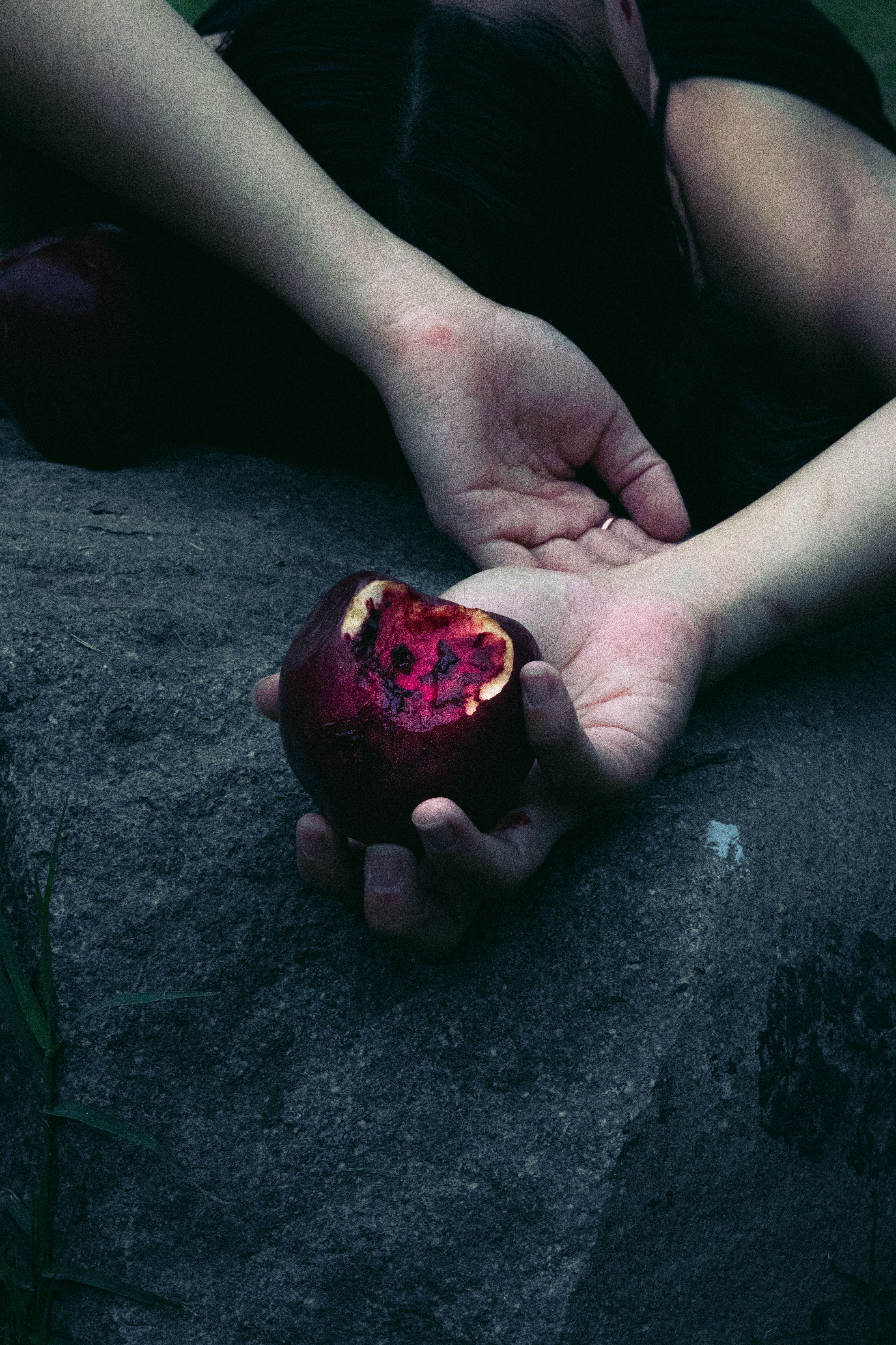 A dark, moody image of a bitten apple in hand, evoking mystery.