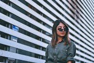 一位戴着墨镜的年轻女子在条纹城市背景下摆着姿势，散发着时尚气息