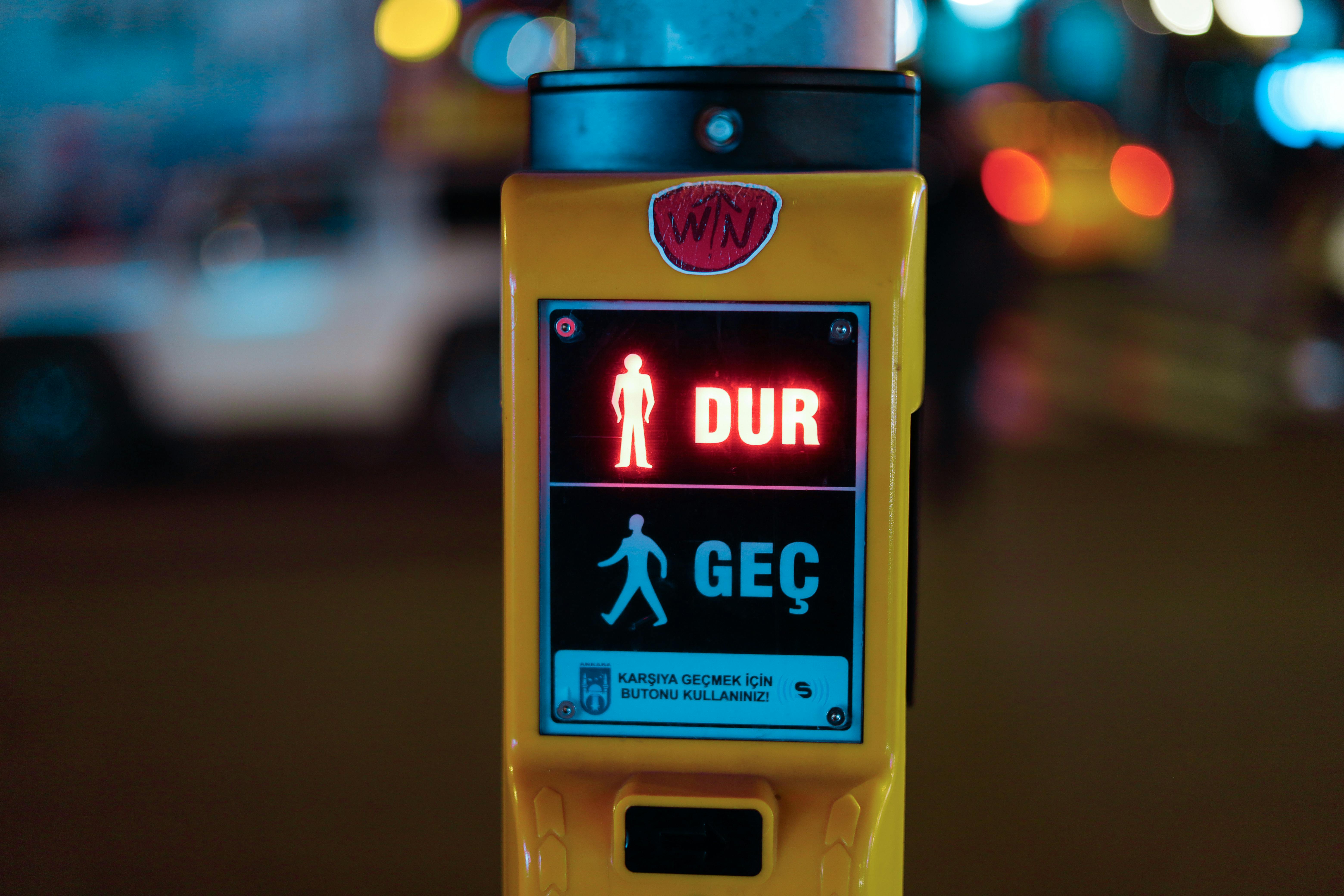 Close-up of a pedestrian traffic light showing stop in Turkish at night.