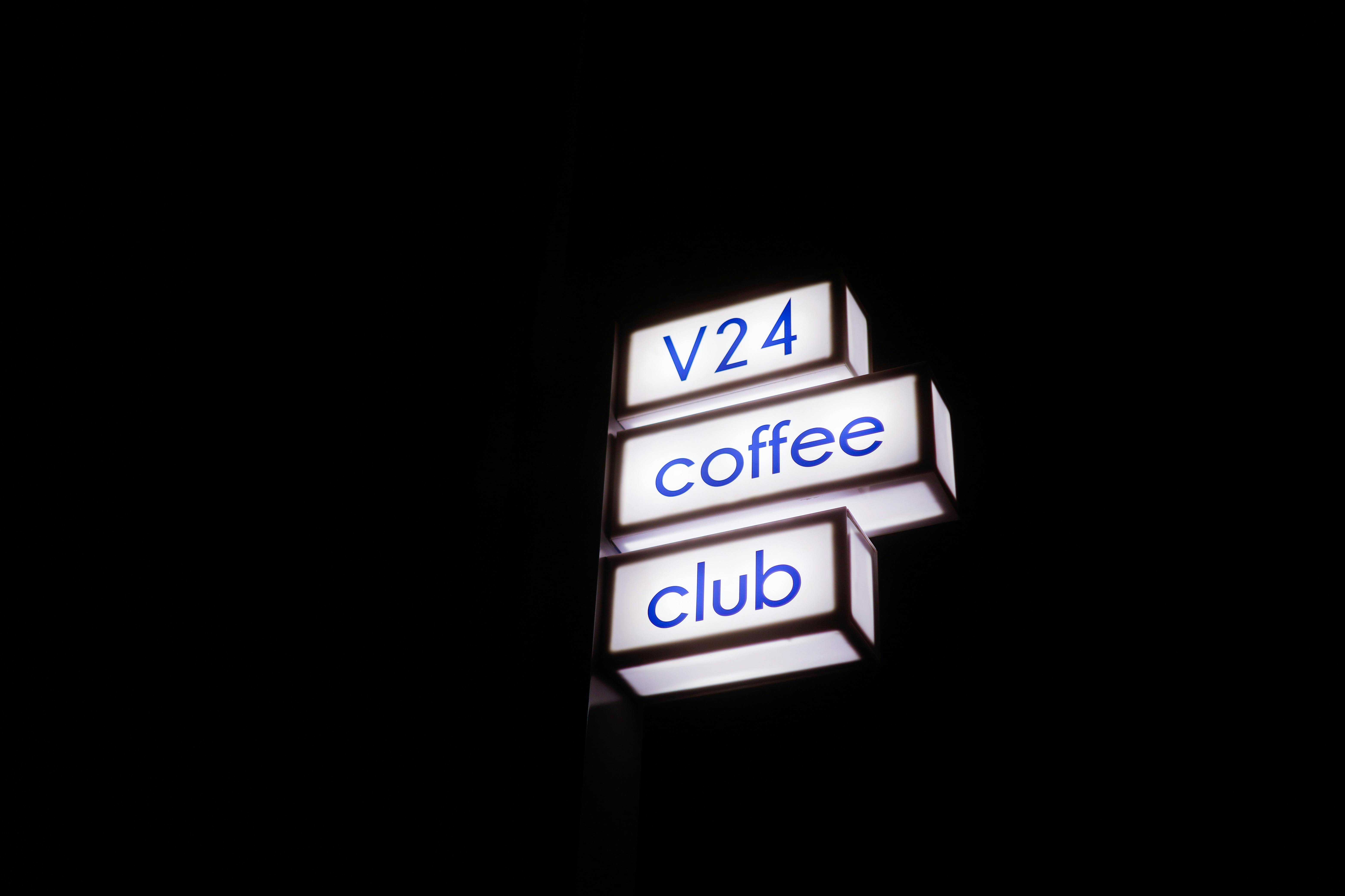 Gratuit Panneau du V24 Coffee Club brillamment éclairé avec un ciel nocturne sombre en arrière-plan. Photos