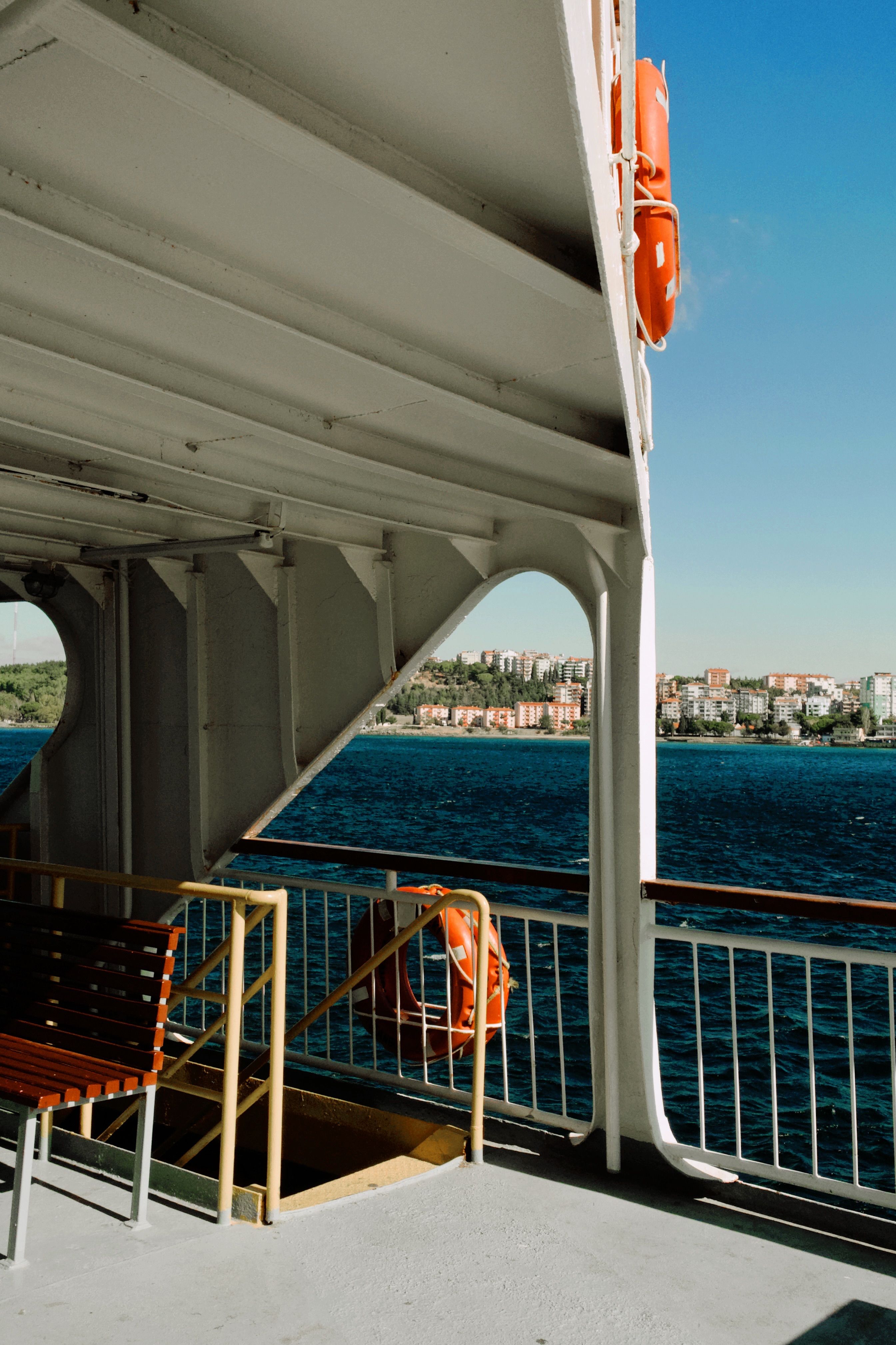 View from a ferry featuring a coastal city and blue ocean under clear skies.