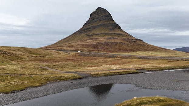 Iconic Kirkjufell Mountain landscape with tranquil waters and cloudy sky in Iceland.