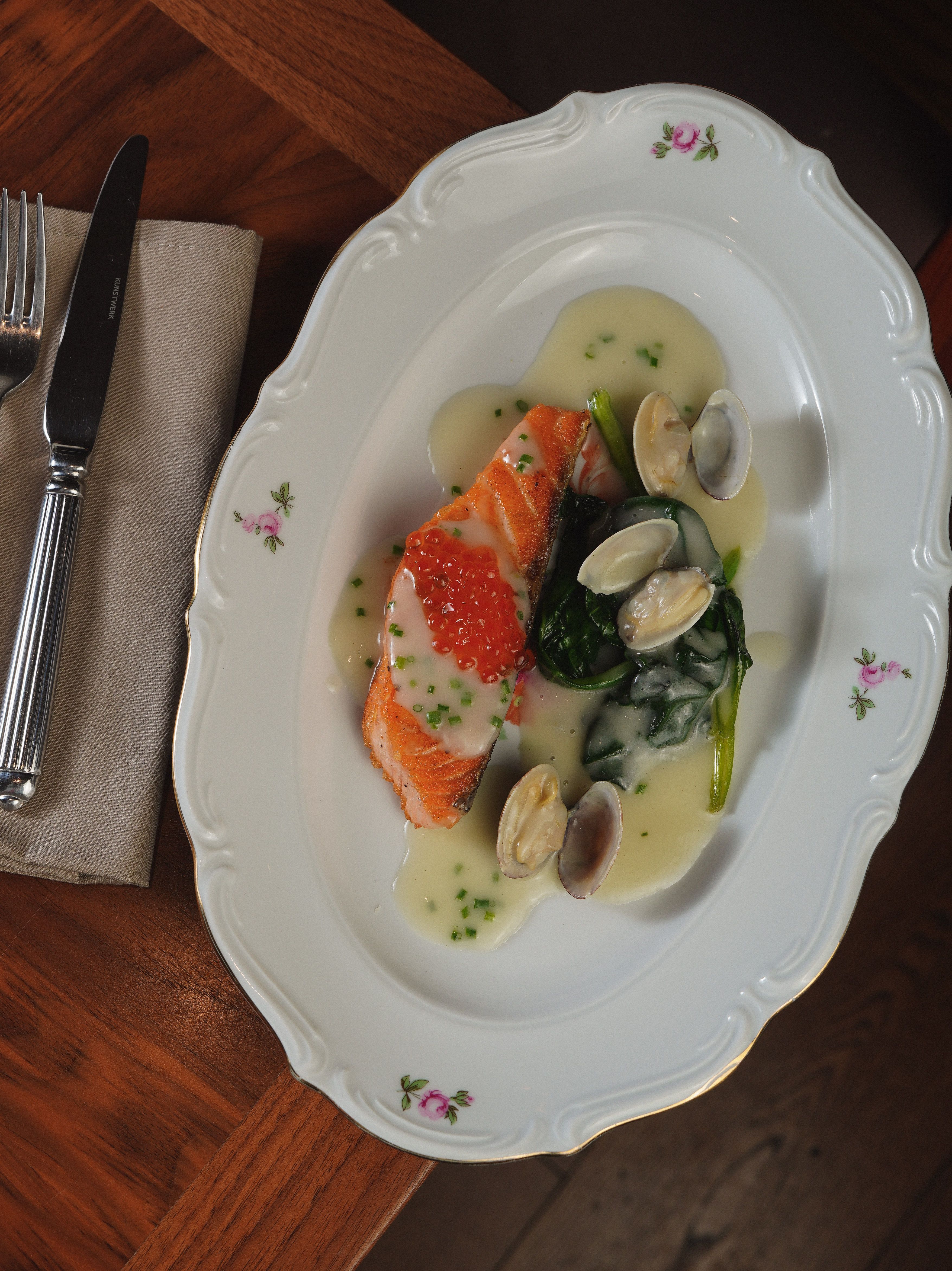 Gourmet salmon and clam platter with sauce, perfect for fine dining photography.