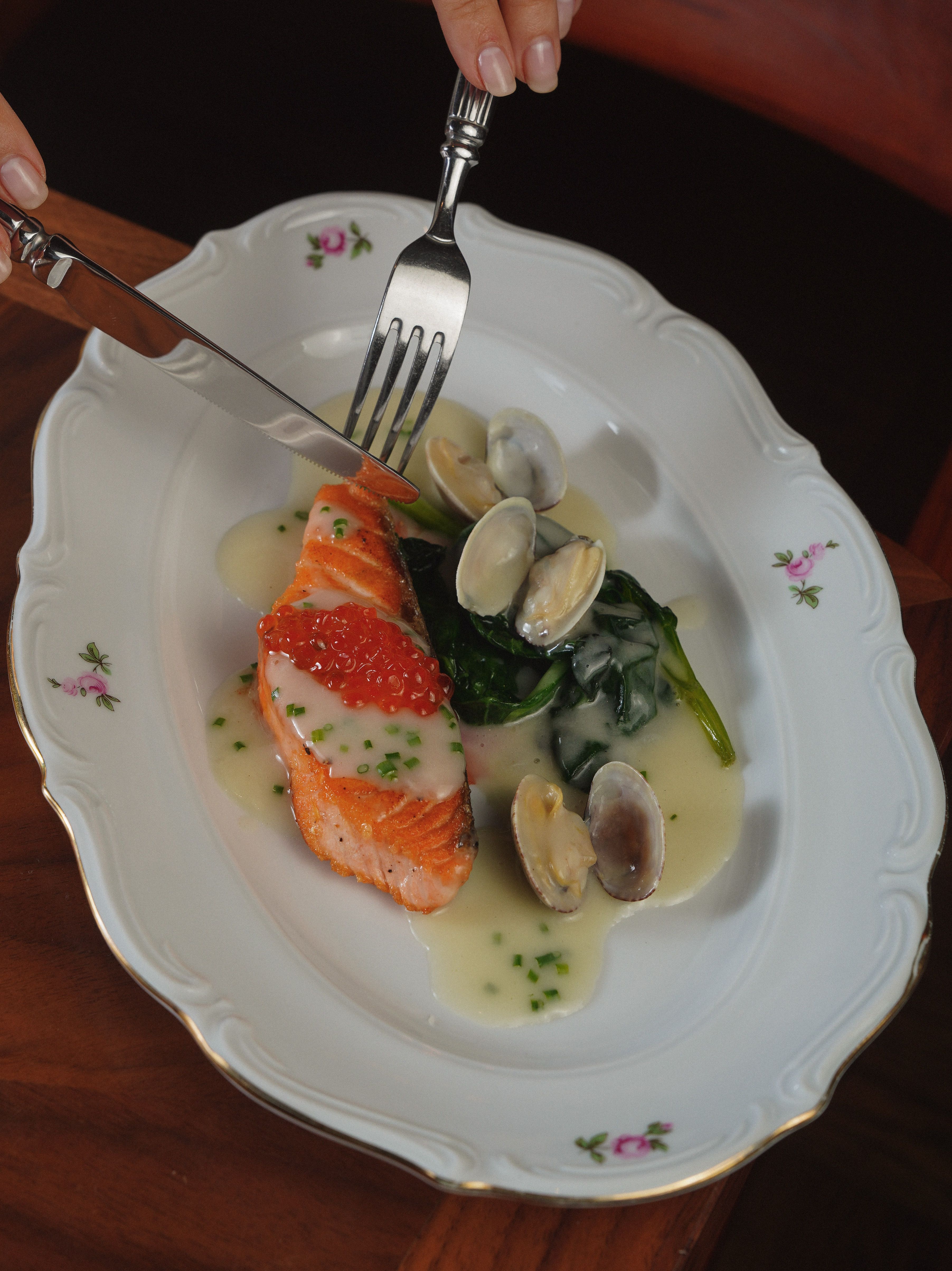 Elegant serving of salmon with clams, spinach, and creamy sauce.