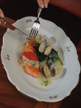 Elegant serving of salmon with clams, spinach, and creamy sauce.