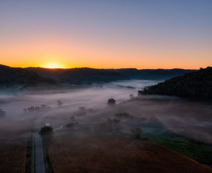 Aerial view of a misty valley at sunrise in Urne, Wisconsin, showcasing serene rural landscapes.