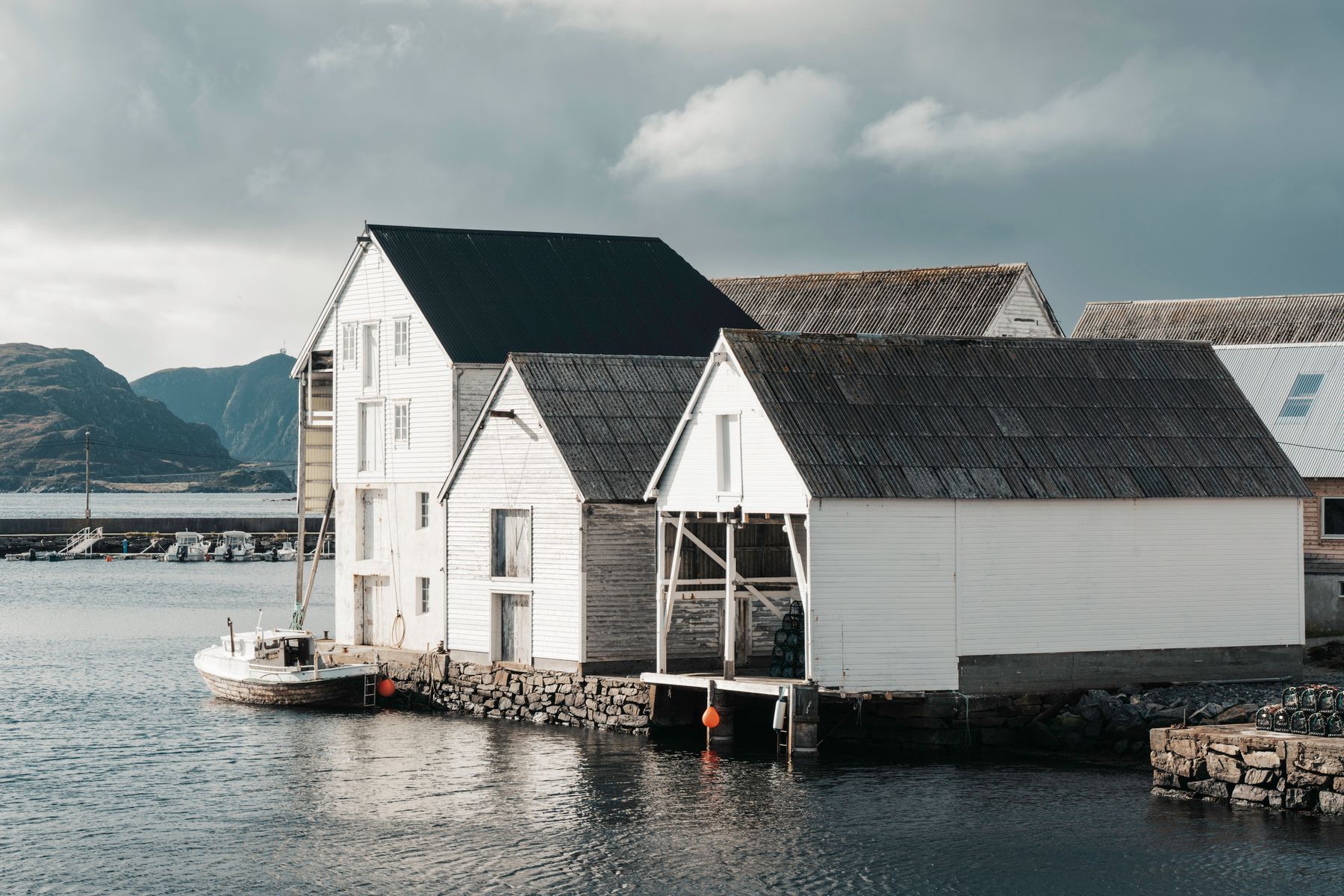 White timber houses and a small boat in a coastal fishing village, photo by Raul Ling on Pexels