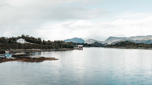 Free Tranquil fjord scene with mountain backdrop and rustic wooden hut in Norway. Stock Photo
