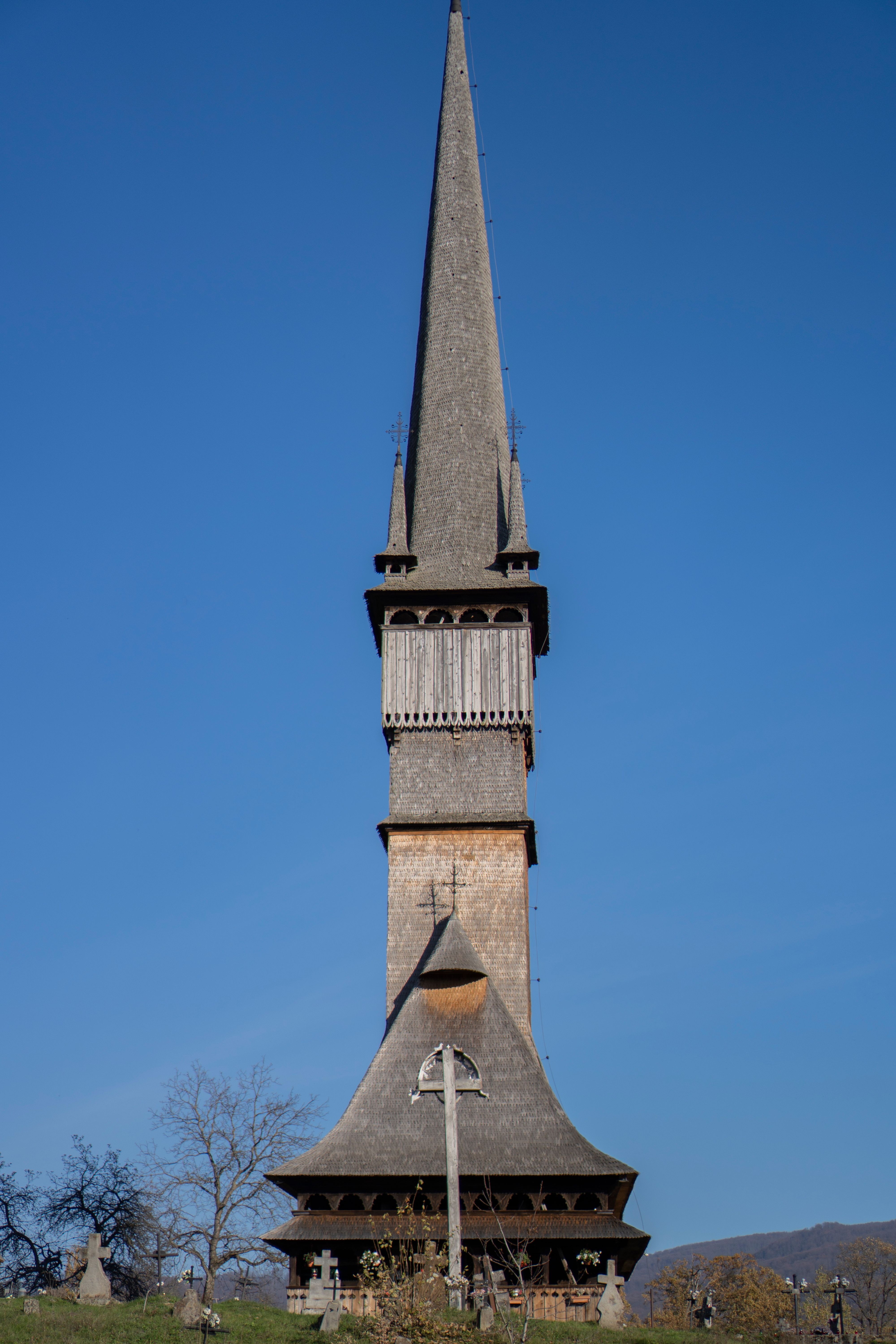 A historic wooden church tower in Surdesti, Romania, showcasing traditional architectural elements.