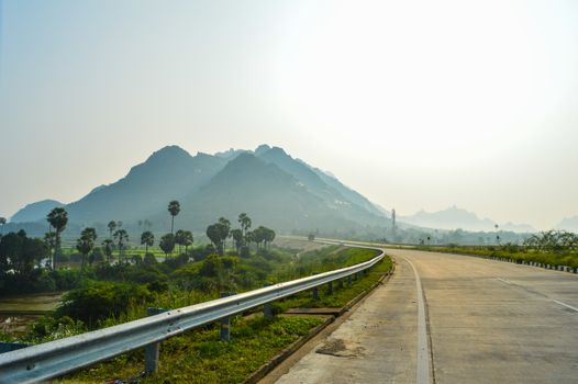 Scenic view of a mountainous highway surrounded by lush greenery under a clear sky.
