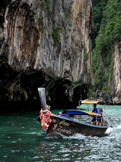 Free Explore the serene beauty of a traditional long-tail boat navigating through Thai cliffs. Stock Photo