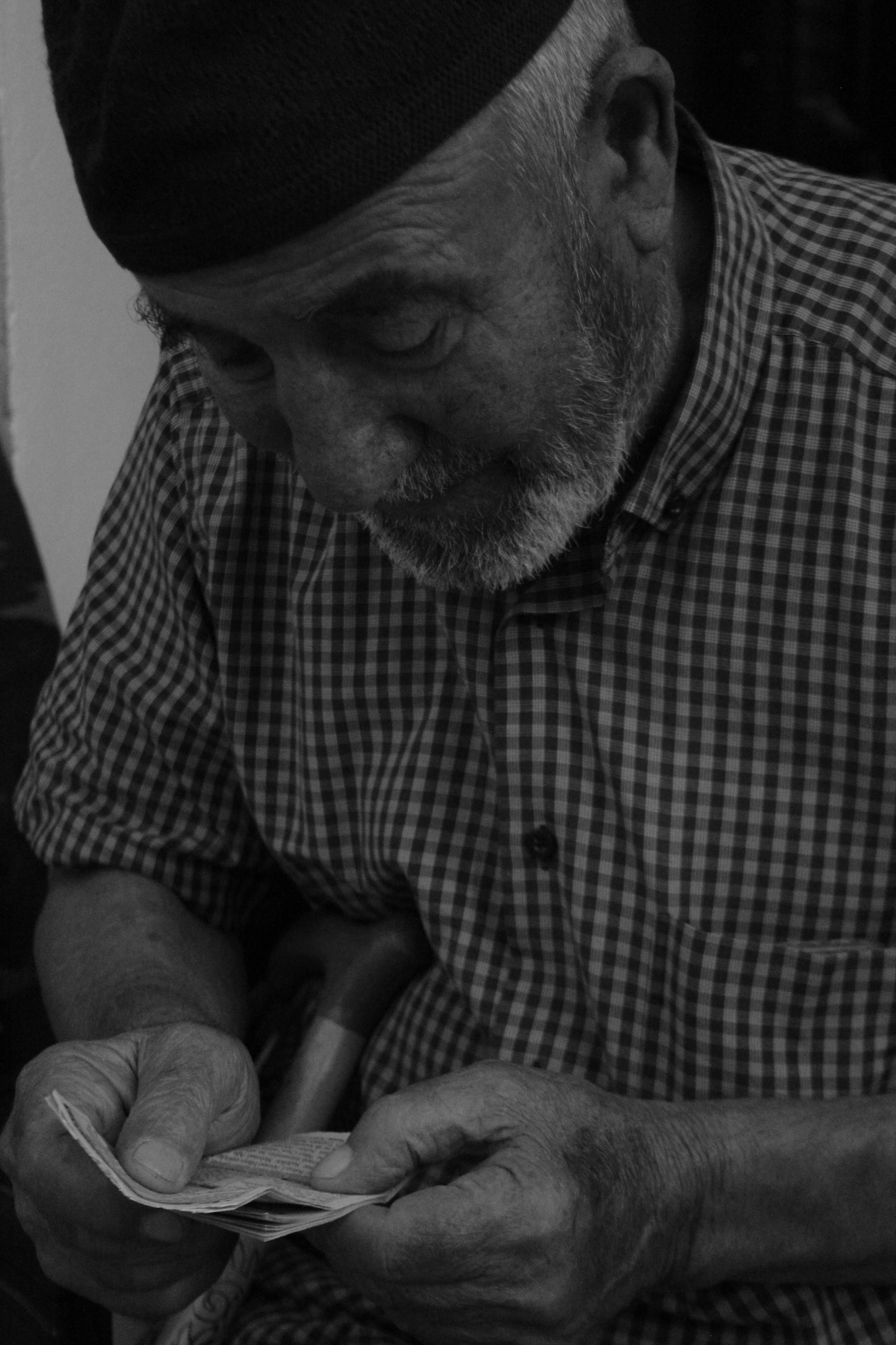 Black and white photo of an elderly man counting money on the streets of Samsun, Türkiye.