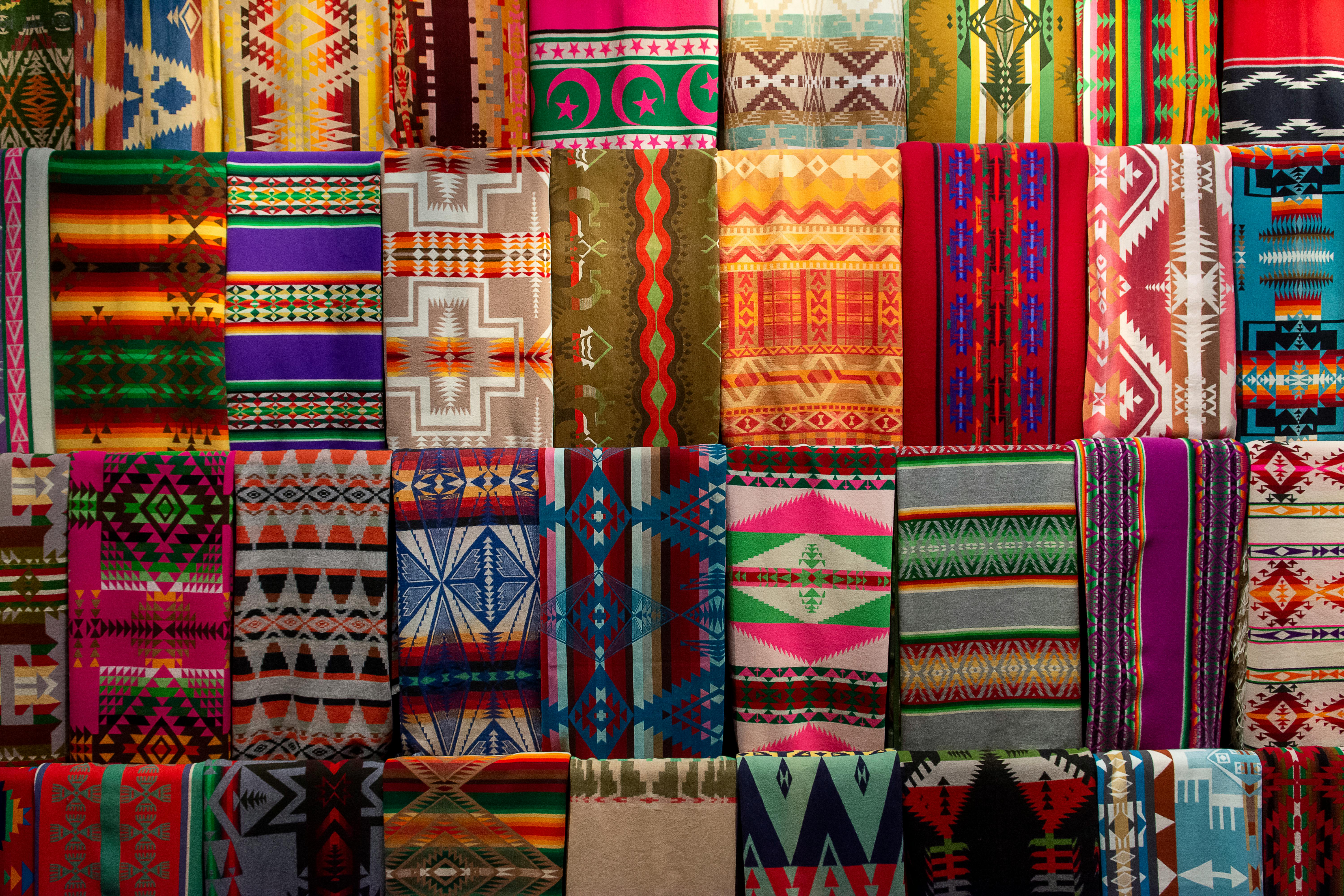 Vibrant collection of colorful traditional textiles with geometric patterns on display.