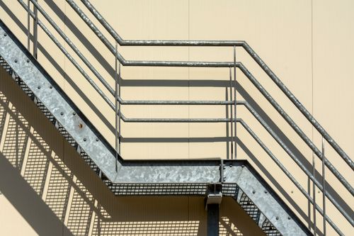 Free Metal fire escape stairs casting shadows on a wall in sunlight. Stock Photo