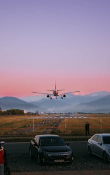 Airplane descends over Batumi, Georgia at sunset, with vivid pink sky.