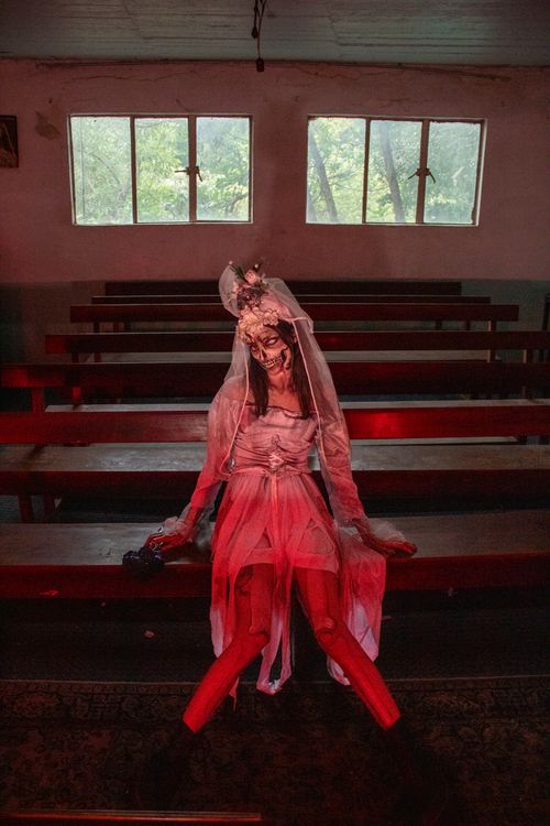 Free A person in a haunting Halloween costume sitting alone inside an empty abandoned church. Stock Photo