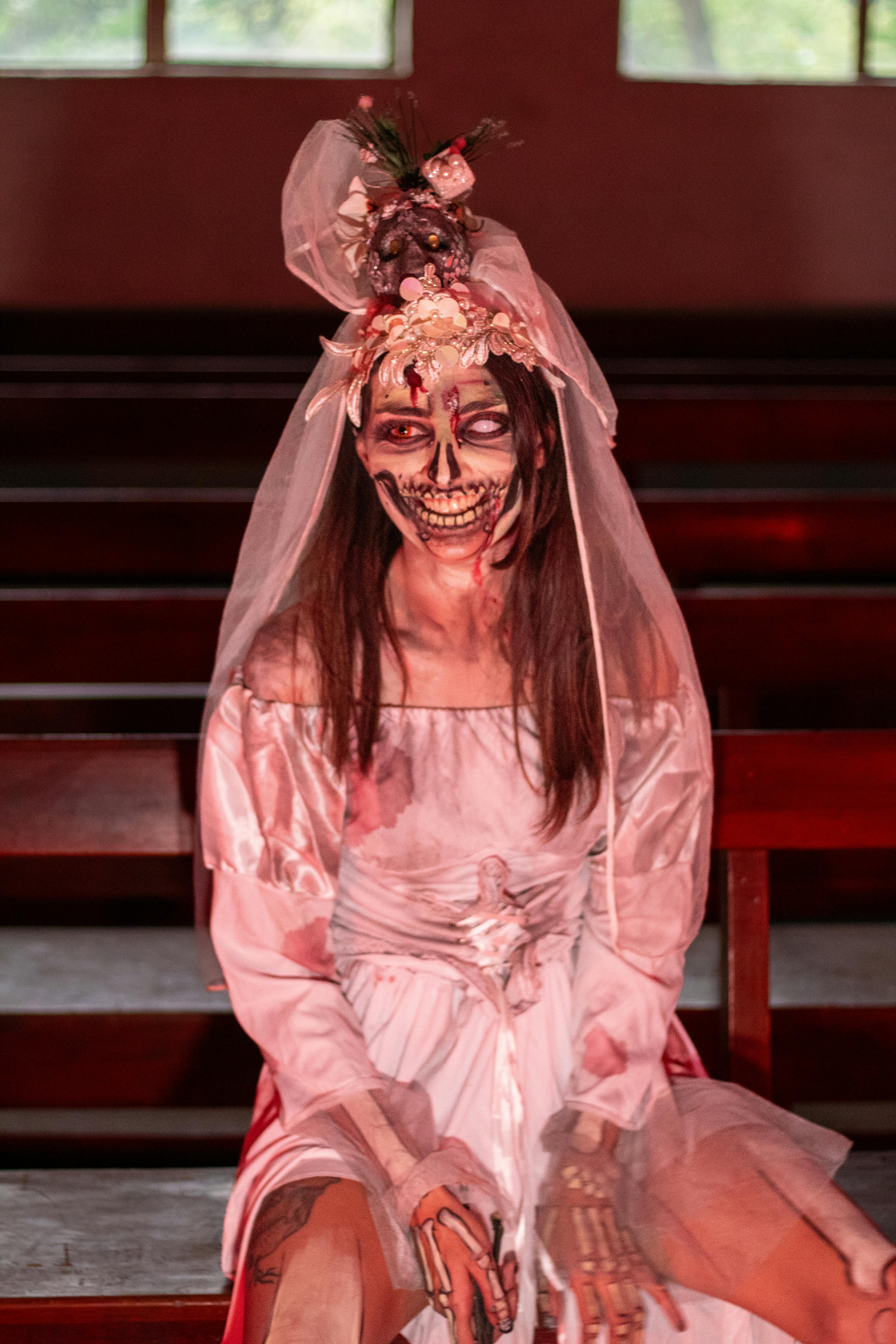 Ücretsiz Loş ışıklı bir kilise sırasına oturan Cadılar Bayramı temalı zombi gelin. Stok Fotoğraflar