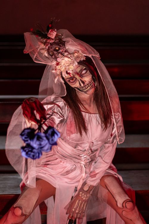 Free A person in a Halloween costume with skeletal makeup and flowers sitting on a staircase. Stock Photo