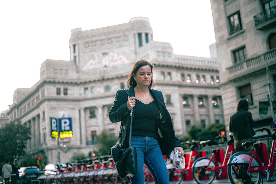 Mujer caminando junto a bicicletas en la ciudad con un fondo de arquitectura histórica. Paisaje urbano capturado durante el día.
