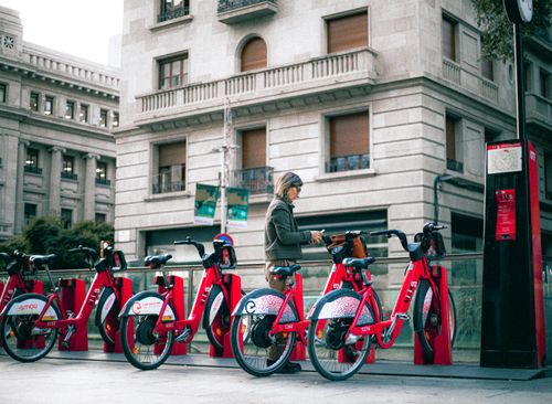 Free A person at a bike-sharing station in an urban city, surrounded by buildings. Stock Photo