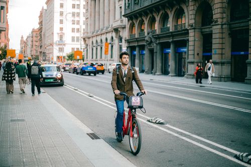 Free Man cycling on city street in an urban setting with historic architecture. Stock Photo
