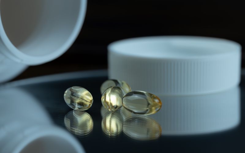 Focused image of gel capsules with a white bottle cap, emphasizing health and supplements.