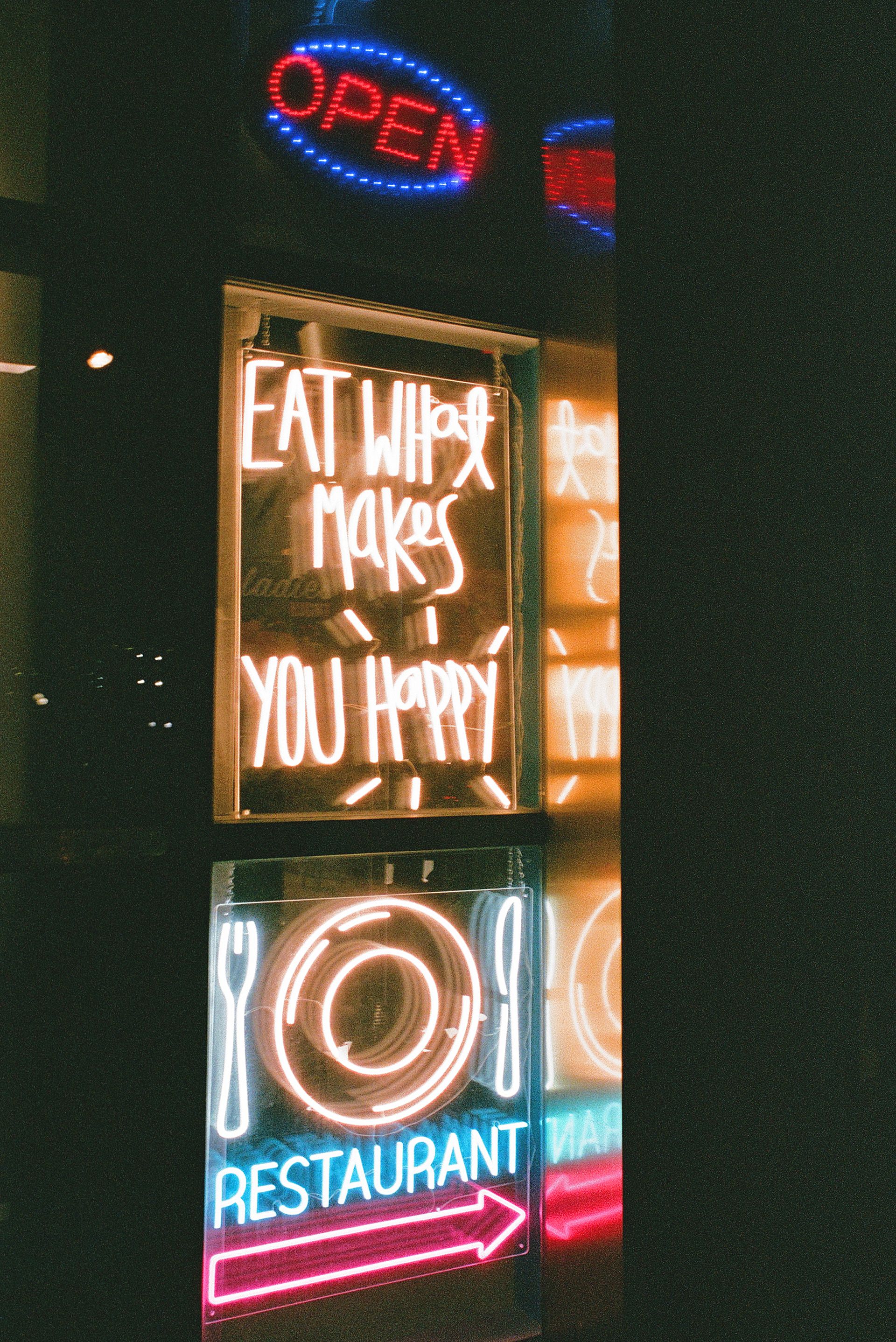 Stack of glowing neon signs in a shopfront window at night