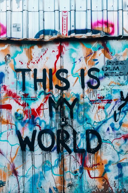 Colorful graffiti mural reading 'THIS IS MY WORLD' on urban metal wall.