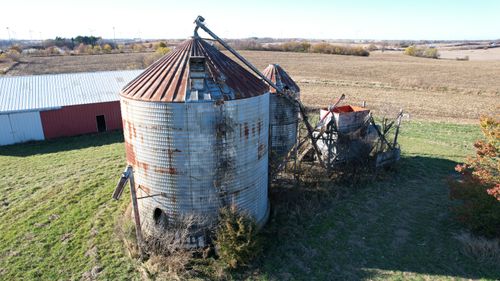 Free Aerial view of weathered farm silos in a vast rural landscape under a clear sky. Stock Photo